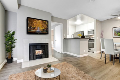 A modern living room with a fireplace and a painting of a tree-lined road.