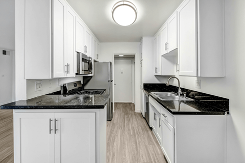 A kitchen with white cabinets and black countertops.