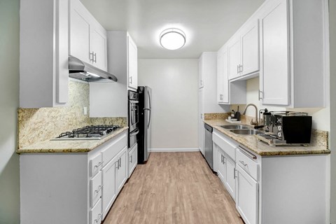 A kitchen with white cabinets and a granite countertop.