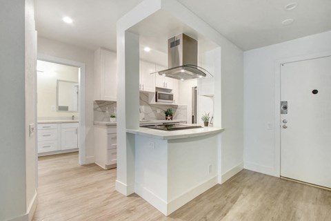 A modern kitchen with white cabinets and a wooden floor.