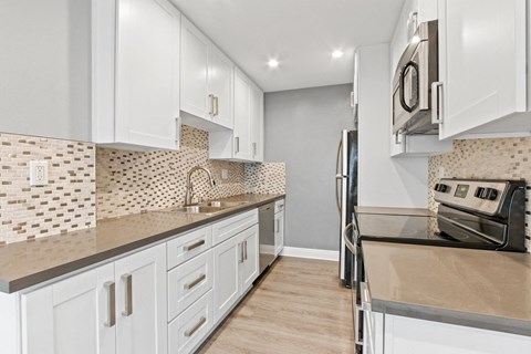 A kitchen with white cabinets and a tile backsplash.
