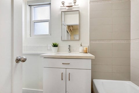 A white bathroom with a tub, sink, and mirror.