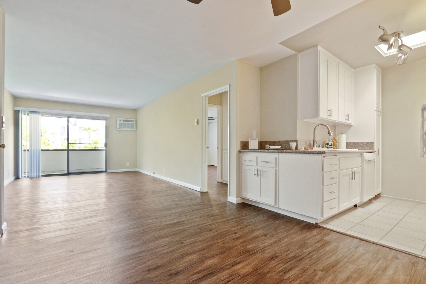 A kitchen with white cabinets and a wooden floor.