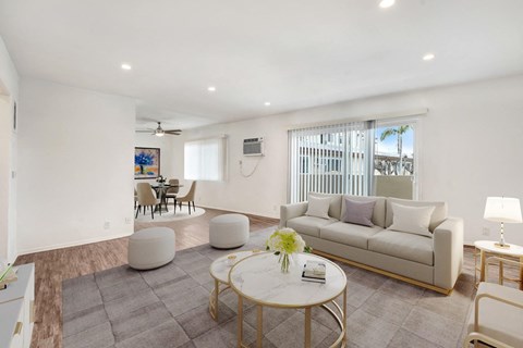 A living room with a white couch, a coffee table, and a painting on the wall.