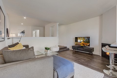 A grey couch sits in a living room with a television and a fireplace.