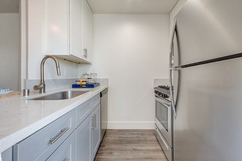 A kitchen with a stainless steel refrigerator and a sink with a faucet.