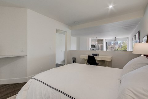 A bedroom with a large bed and a desk with a chair.