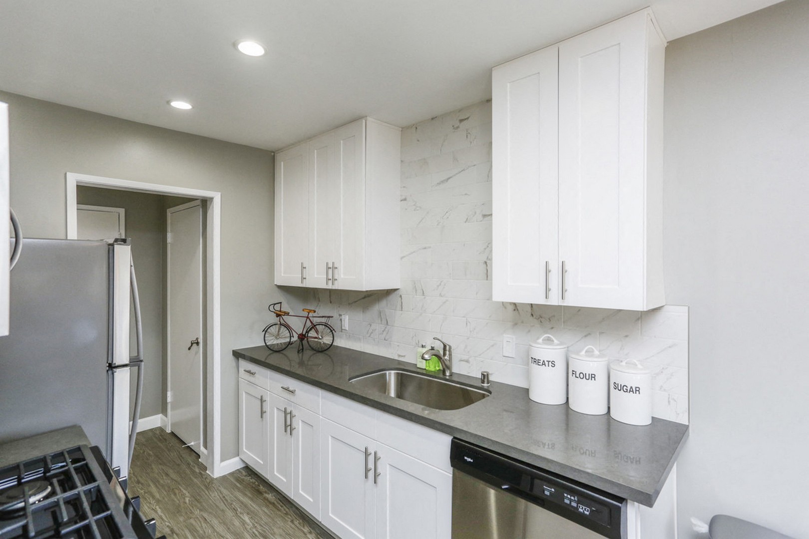 A kitchen with white cabinets and a black dishwasher.