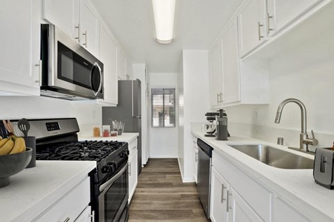 A modern kitchen with white cabinets and stainless steel appliances.
