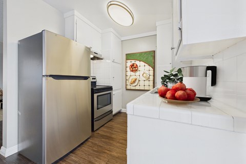 A modern kitchen with a stainless steel refrigerator and a white countertop.