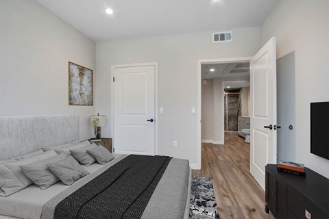A bedroom with a large bed and a television on the wall.