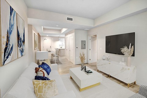 A living room with a white couch and a large painting on the wall.