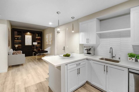 A modern kitchen with white cabinets and a wooden floor.
