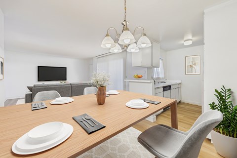A modern dining room with a wooden table set for two.