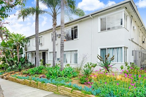 A white two-story building with a garden in front.