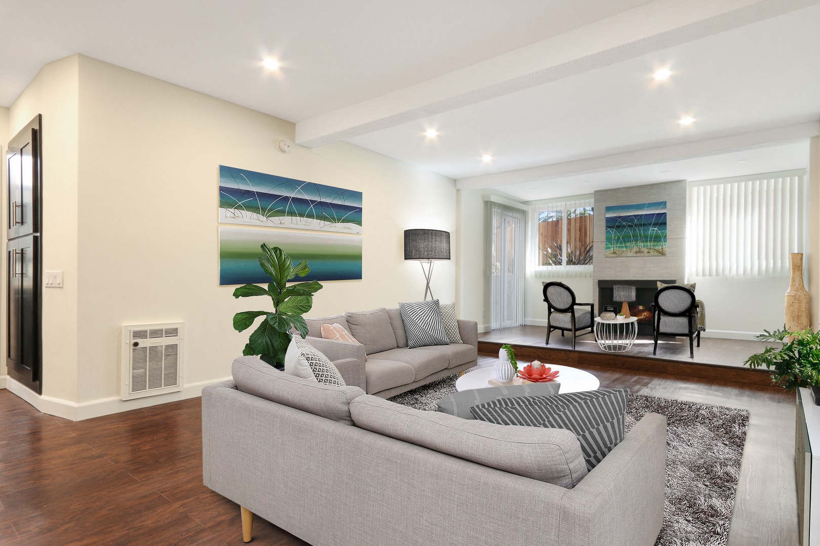 A living room with a grey couch and a painting on the wall.