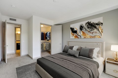 A bedroom with a large bed and a painting on the wall.