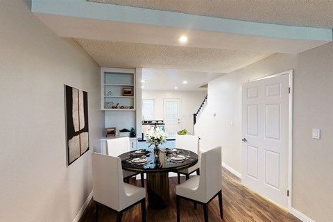 A dining room with a table set for two and a painting on the wall.