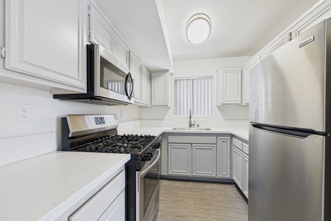 A modern kitchen with white cabinets and stainless steel appliances.