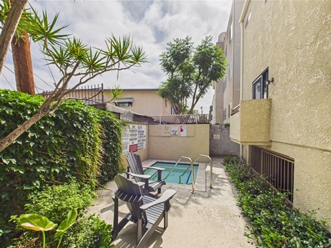 A small pool surrounded by a concrete patio and a black metal railing.