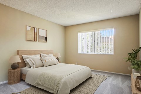 A bedroom with a large bed and a window with blinds.