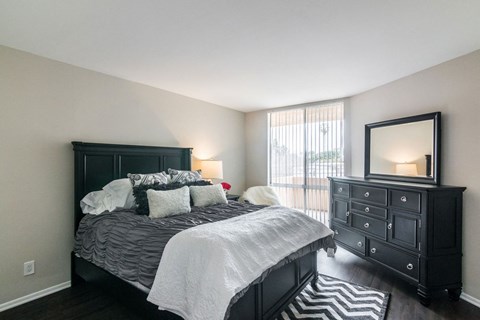 A bedroom with a large bed and a dresser with a mirror.