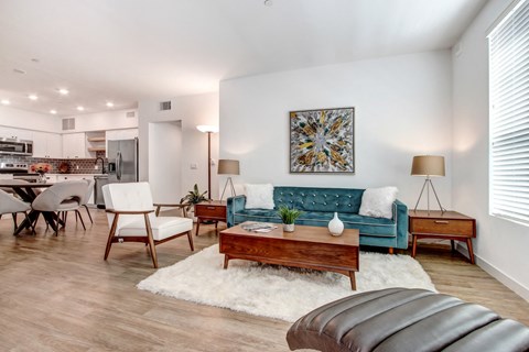 A living room with a blue couch and a white rug.