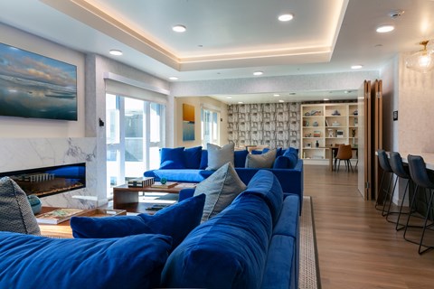 A living room with a blue couch and a painting on the wall.