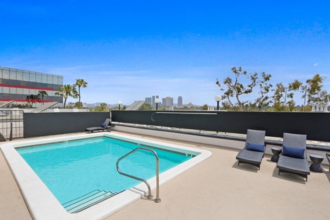 the pool on the rooftop of an apartment building with chairs and a pool