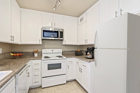 A kitchen with white cabinets and appliances.