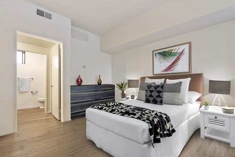 A bedroom with a large bed and a painting above it.