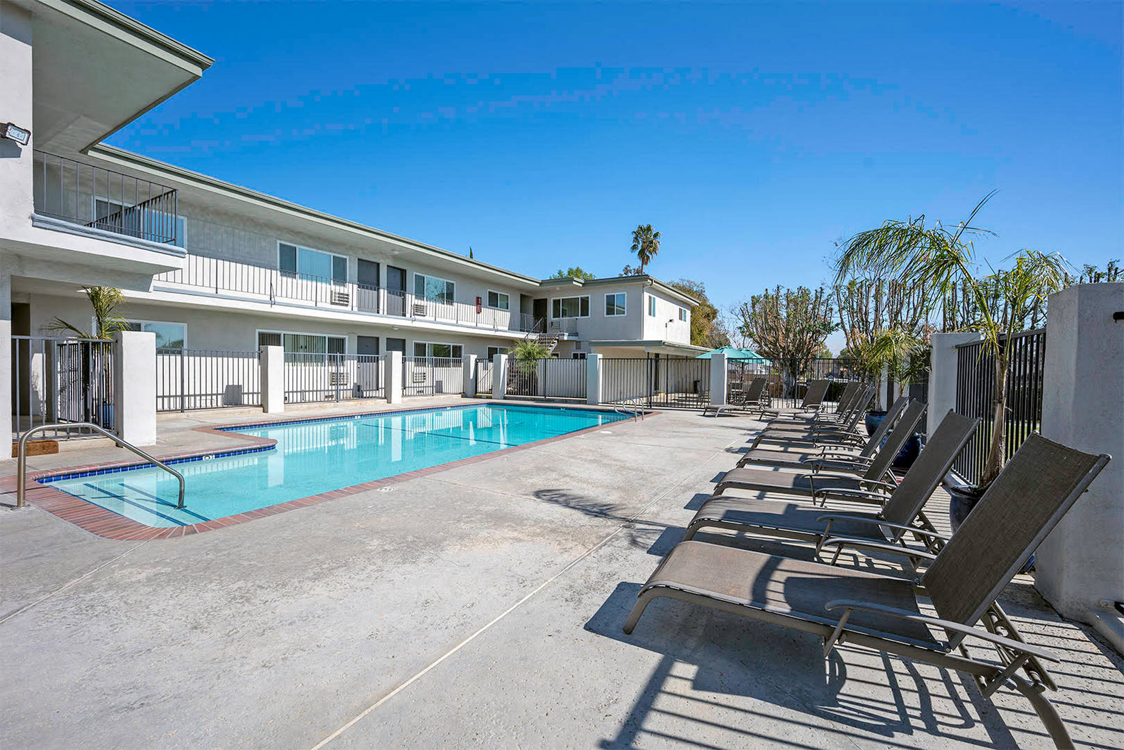 A pool area with sun loungers and a building in the background.
