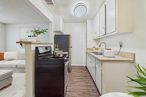 A modern kitchen with a black stove top oven and white cabinets.