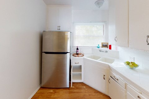 A small kitchen with a refrigerator, sink, and counter.