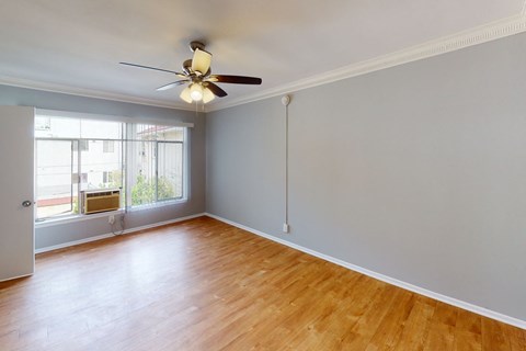A room with a ceiling fan and a window with blinds.