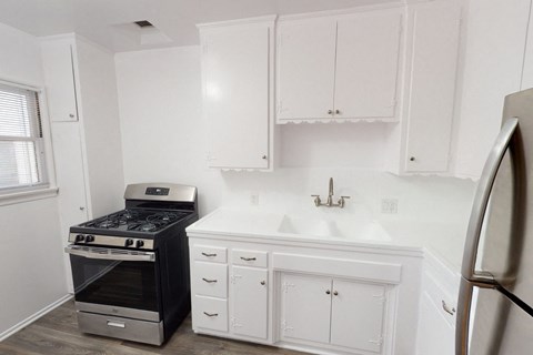 A kitchen with white cabinets and a black stove.