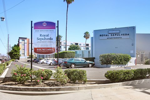 A sign for Royal Sepulveda Apartments is displayed in front of a building.