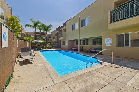 A small pool surrounded by a concrete patio and a building.