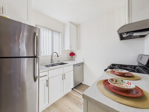 A modern kitchen with a stainless steel refrigerator and white cabinets.