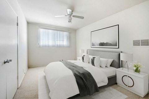 A bedroom with a large bed and a ceiling fan.