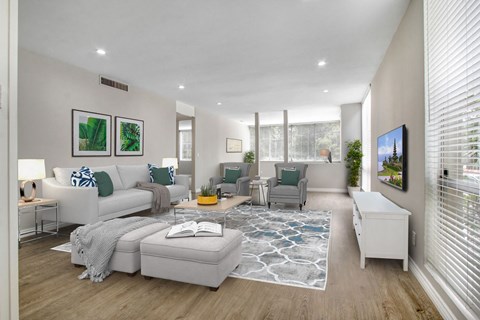 A living room with a white couch, a grey armchair, a white coffee table, and a white side table.