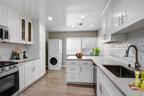 A modern kitchen with white cabinets and appliances.