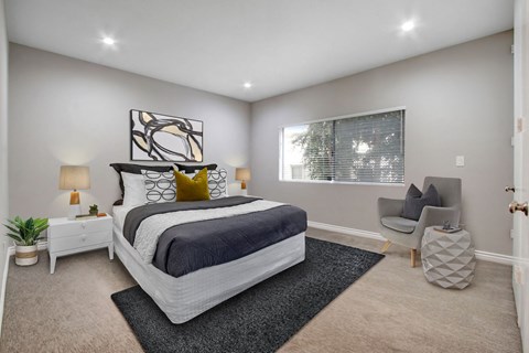 A bedroom with a large bed and a chair.