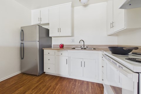 A kitchen with white cabinets and a stainless steel refrigerator.