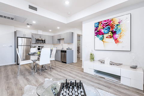A modern kitchen with a glass table and a painting on the wall.
