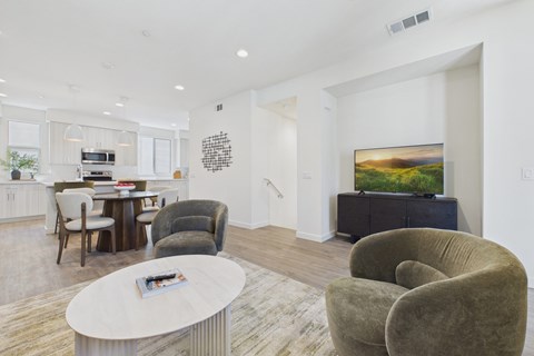 A living room with a grey couch, a white coffee table, and a painting on the wall.