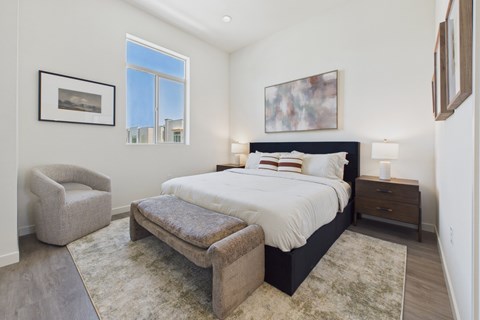 A bedroom with a large bed and a chair.