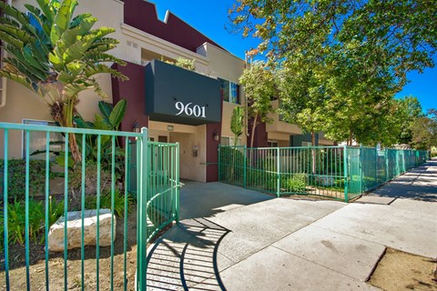 A green fence surrounds a building with the number 9601 on it.