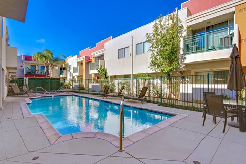 A pool surrounded by a white fence and chairs.