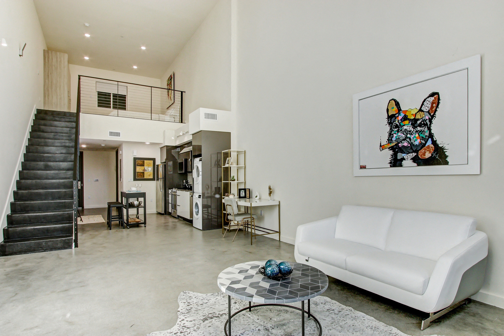 A living room with a white couch, a coffee table, and a painting of a dog.
